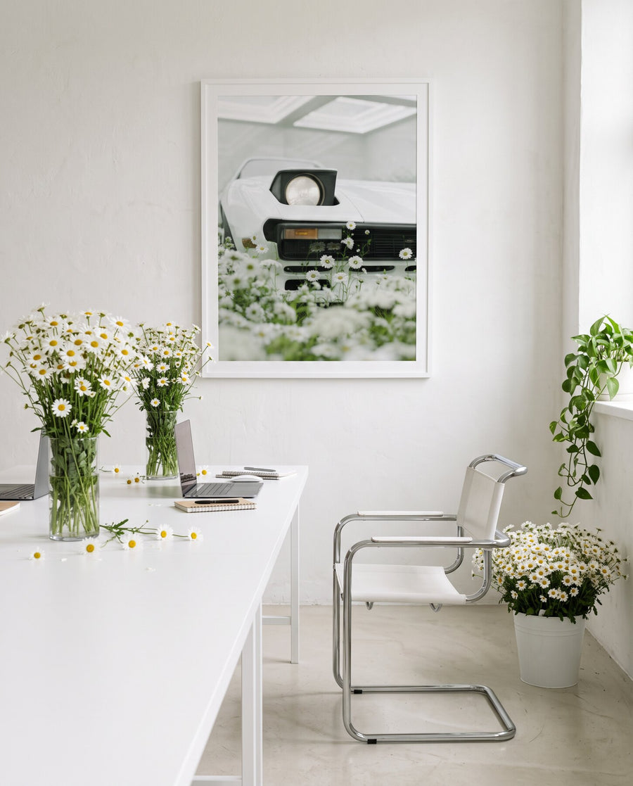 WHITE 02 framed above a white desk with vases of white daisies