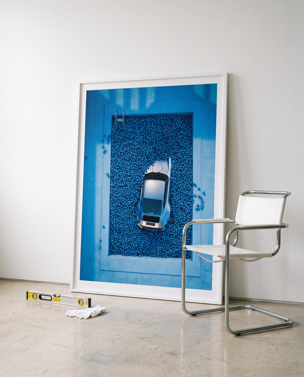 AZUR 02 framed, leaning against a white wall next to a chrome chair